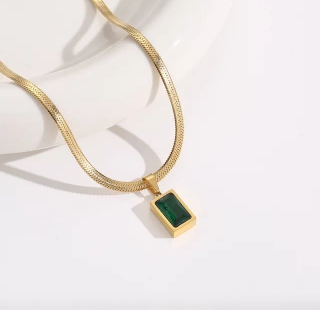 Gold chain necklace with a rectangular green gemstone pendant.