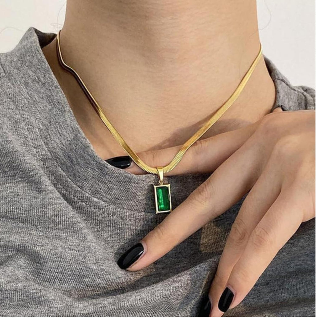 Gold chain necklace with a rectangular green gemstone pendant.